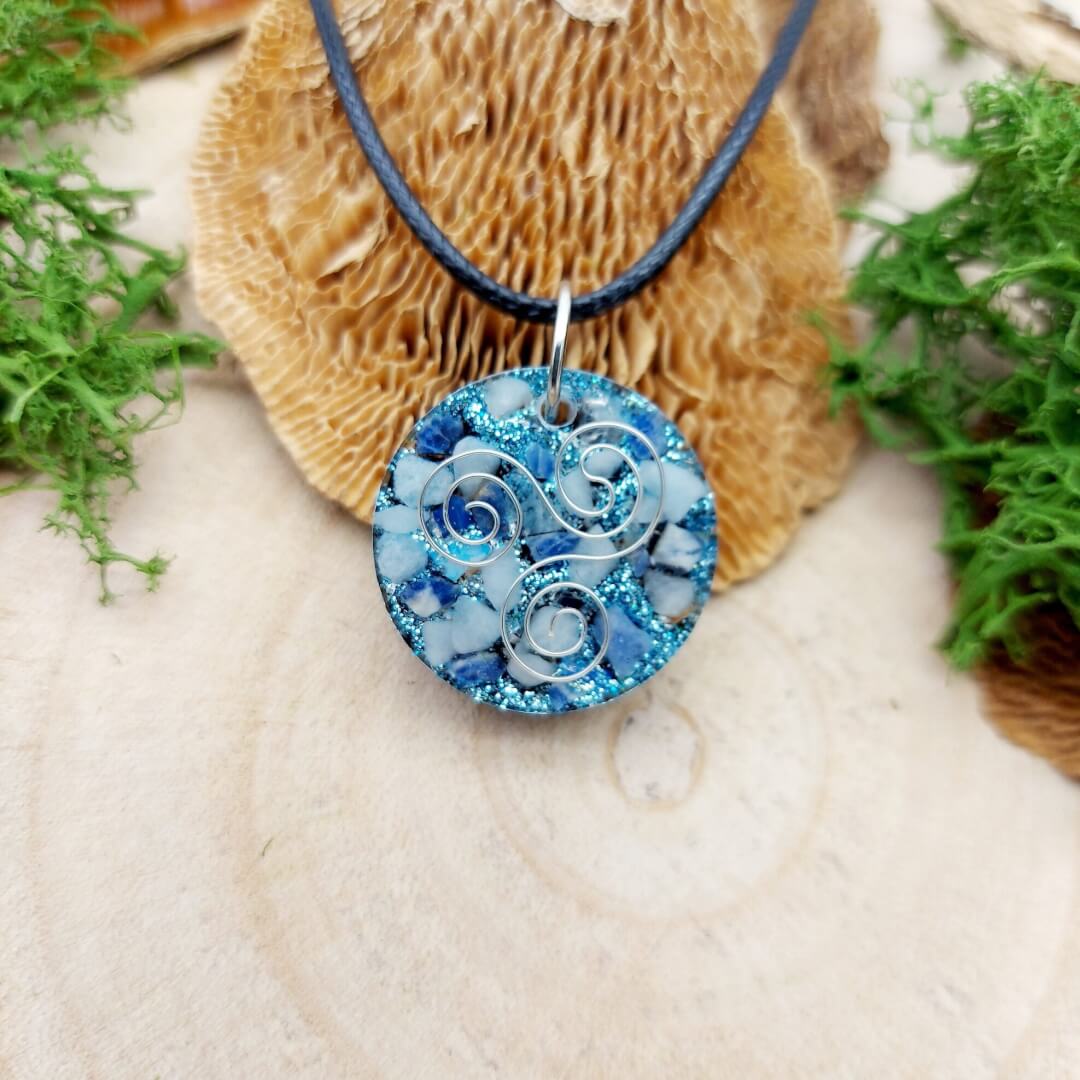 orgonite hanger rond wit, blauw met triskelion zilver