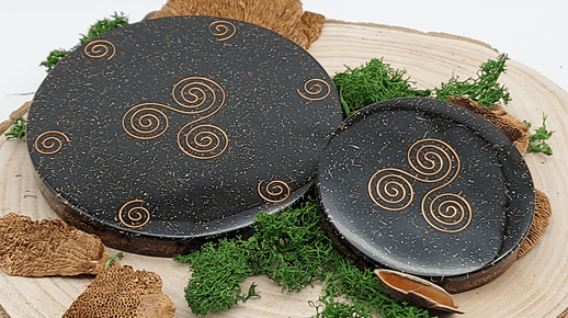 twee orgonite oplaadschijven zwart met koperen triskelion en spiralen